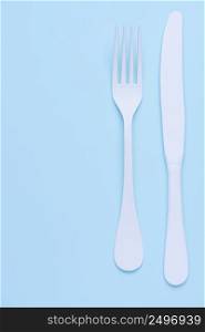 Knife and fork on trendy blue pastel background with side copy space vertical composition