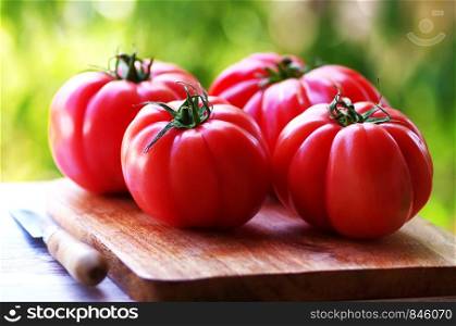 knife and red tomatoes on wooden table