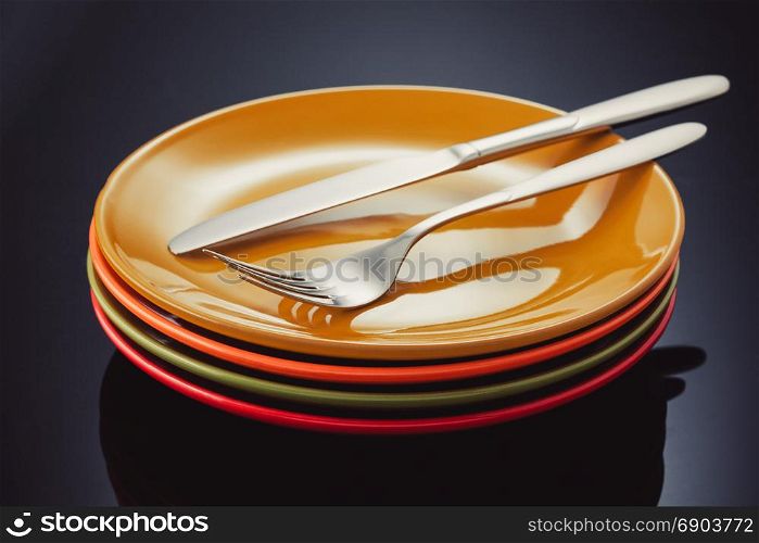 knife, fork and plate at glossy black background