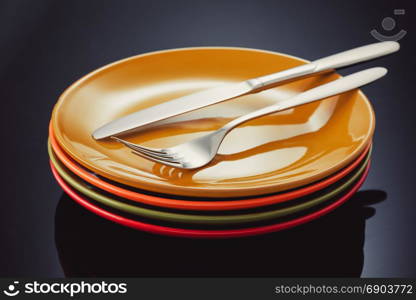 knife, fork and plate at glossy black background