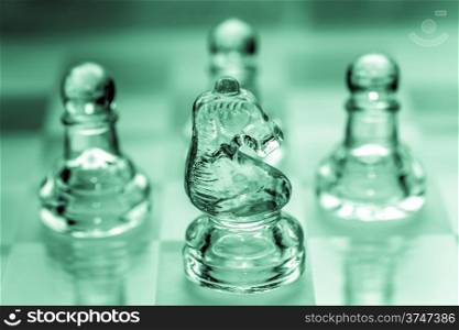 Knight chess piece with pawns in the background pieces made out of glass