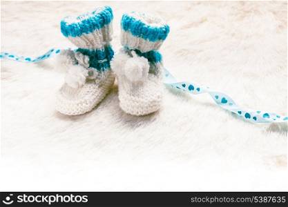 Knitted blue baby booties for little boy with copy space