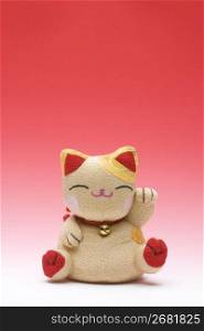 Knitted chinese waving cat isolated on red background