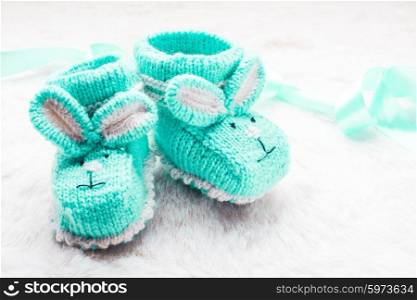 Knitted green baby booties with rabbit muzzle for little boy. Knitted baby booties