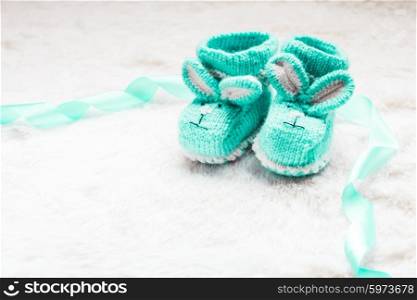 Knitted green baby booties with rabbit muzzle for little boy. Knitted baby booties
