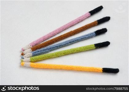 Knitted pencil, handmade gift, nice craft from yarn, group of colorful with shade on wooden background or white background