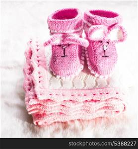 Knitted pink baby booties and blanket for little girl