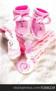 Knitted pink baby booties, toys, blanket for little girl