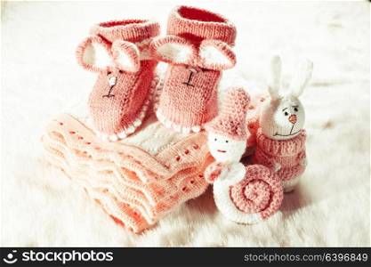 Knitted pink baby booties, toys, blanket for little girl. Knitted baby booties