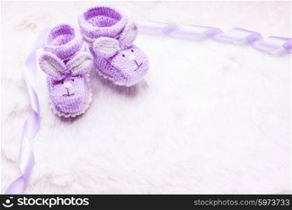 Knitted purple baby booties with rabbit muzzle over fur. Knitted baby booties