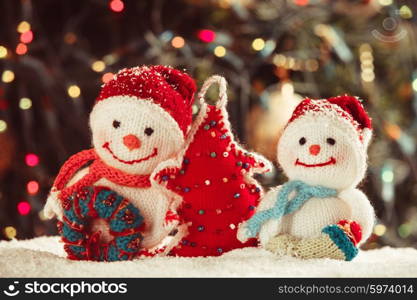 Knitted snowmen and handmade Christmas tree - home decorations on the snow. The Knitted snowmen