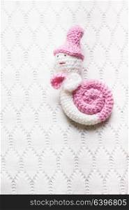 Knitted white with pink snail hung on the wall. Decorative crochet snail