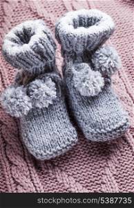 Knitted wool baby booties with pompons close up