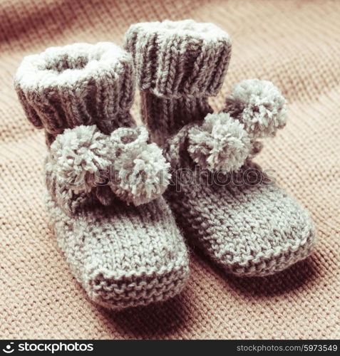 Knitted wool baby booties with pompons close up. Knitted baby booties