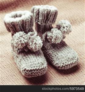 Knitted wool baby booties with pompons close up. Knitted baby booties