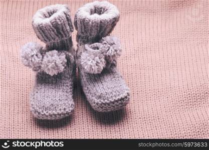 Knitted wool baby booties with pompons close up. Knitted baby booties