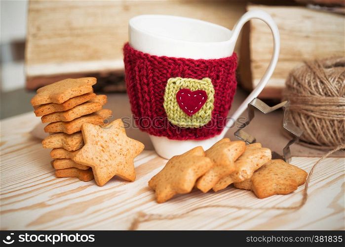 Knitted woolen cups on a wooden table and beautiful delicious christmas gingerbread