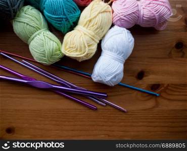 Knitting needles and multicoloured wool on a wooden surface
