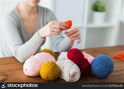 knitting, people and needlework concept - woman pulling yarn up into ball