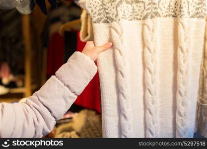 knitwear and people concept - close up of woman buying woolen clothes at christmas market. woman buying woolen clothes at christmas market