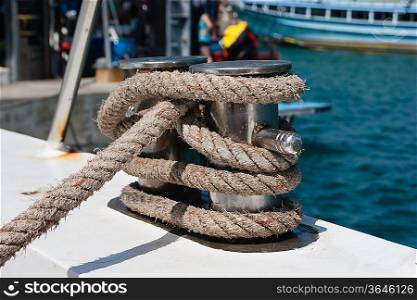 Knot on a bollard of a boat. Blue sea in a background.