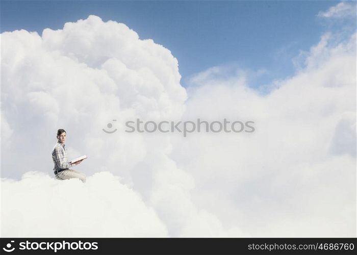 Knowledge advantage. Young man in casual sitting on cloud with book in hands
