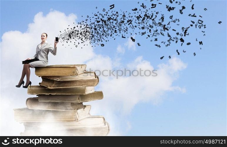 Knowledge advantage. Young woman in suit sitting on pile of old books