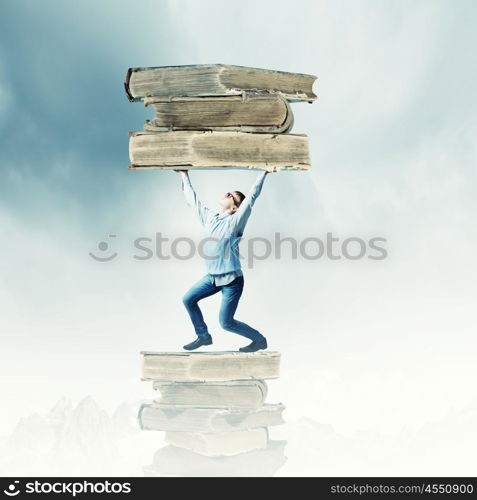 Knowledge and education. Young man holding huge book above head