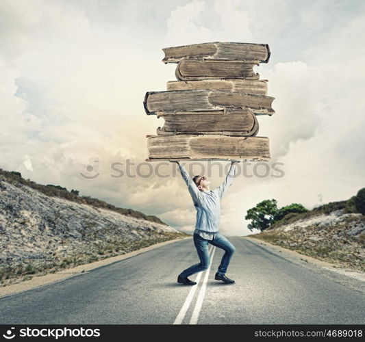 Knowledge and education. Young man holding huge book above head