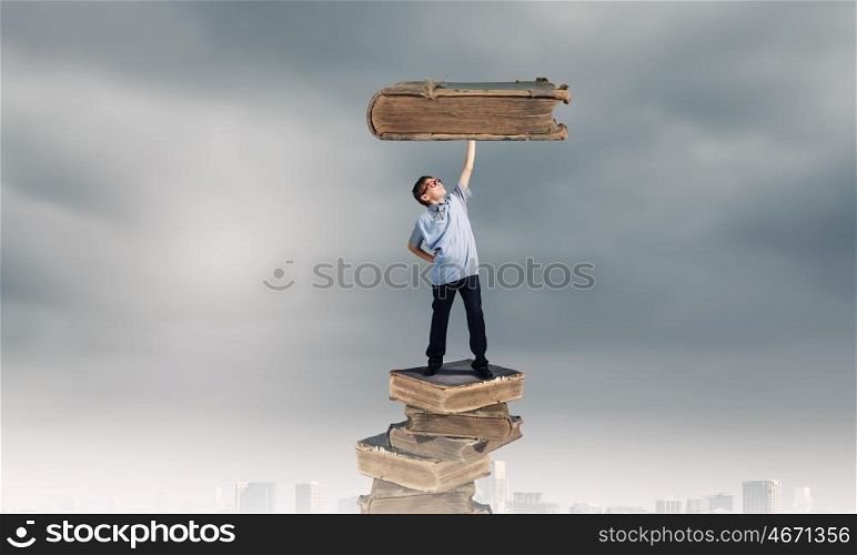 Knowledge and education. Young man holding huge book above head on one hand