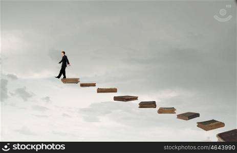 Knowledge as key to success. Businessman walking on career ladder made of books