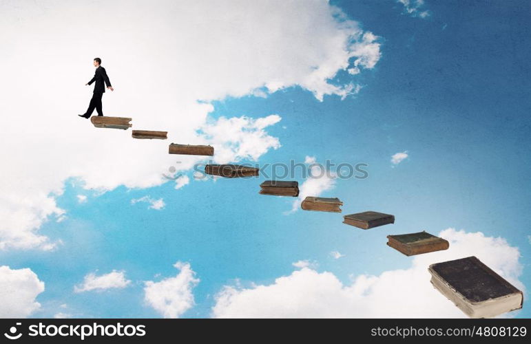 Knowledge as key to success. Businessman walking on career ladder made of books