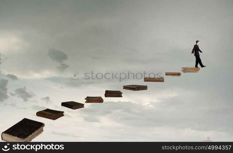 Knowledge as key to success. Businessman walking on career ladder made of books