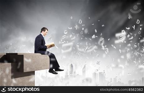 Knowledge concept. Businessman with book sitting on top of building