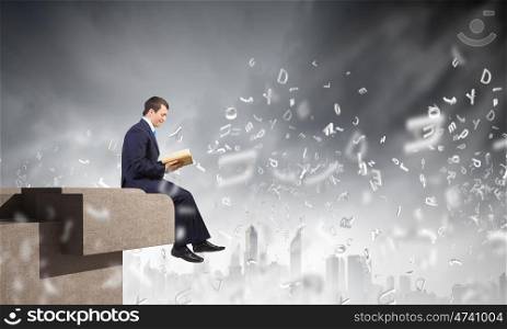 Knowledge concept. Businessman with book sitting on top of building