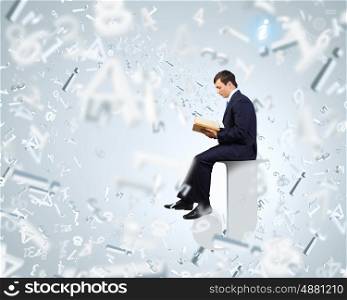 Knowledge concept. Businessman with book sitting on top of huge letter