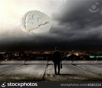 Knowledge concept. Rear view of businessman looking at big brain model