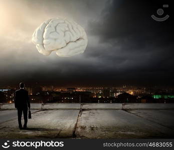 Knowledge concept. Rear view of businessman looking at big brain model