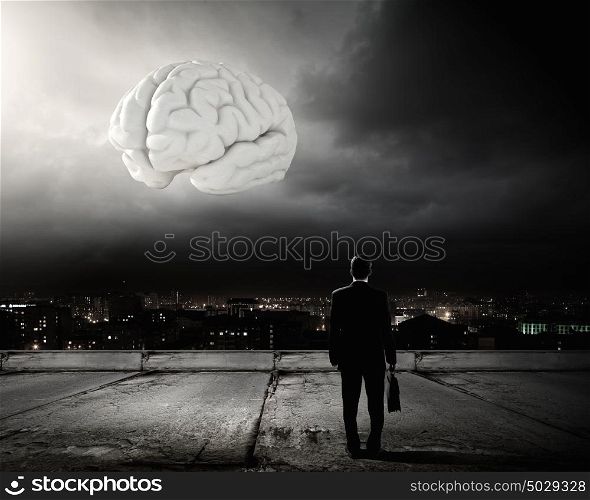 Knowledge concept. Rear view of businessman looking at big brain model