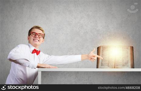 Knowledge concept. Young man in glasses pointing at opened book