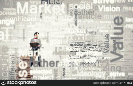 Knowledge is power and future. Young businessman wearing red bow tie sitting with book in hands