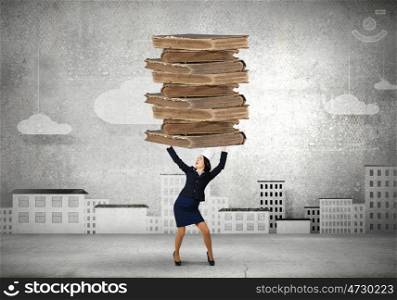 Knowledge is power. Young businesswoman in paper crown lifting books above head