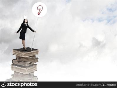 Knowledge is power. Young businesswoman in paper crown standing on pile of books