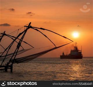 Kochi chinese fishnets on sunset and modern ship. Fort Kochin, Kochi, Kerala, India