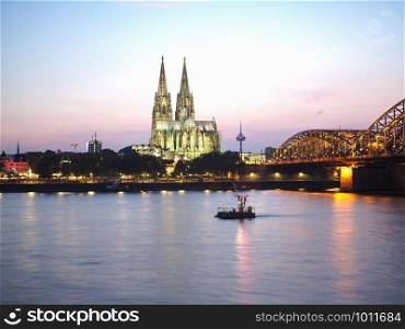 Koelner Dom Sankt Petrus (meaning St Peter Cathedral) gothic church and Hohenzollernbruecke (meaning Hohenzollern Bridge) crossing the river Rhein at night in Koeln, Germany. St Peter Cathedral and Hohenzollern Bridge over river Rhine in Koeln