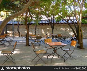 Korean outdoor cafe. Empty tables and chairs outside a traditional stone wall in Seoul, South Korea.