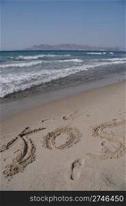 Kos written on a sandy beach in Kos, Greece (Turkey on the background)