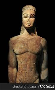 Kouros of the sacred gate ancient greek statue of male figure on black background. Kerameikos museum, Athens Greece.