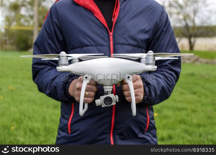 Krasnodar, Russia - May 15, 2017: A man with a quadrocopter in his hands. A white drone is being prepared for the flight. Phantom. A man with a quadrocopter in his hands. A white drone is being p