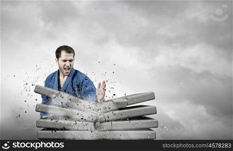Krate man in action. Determined karate man break with hand stone bricks
